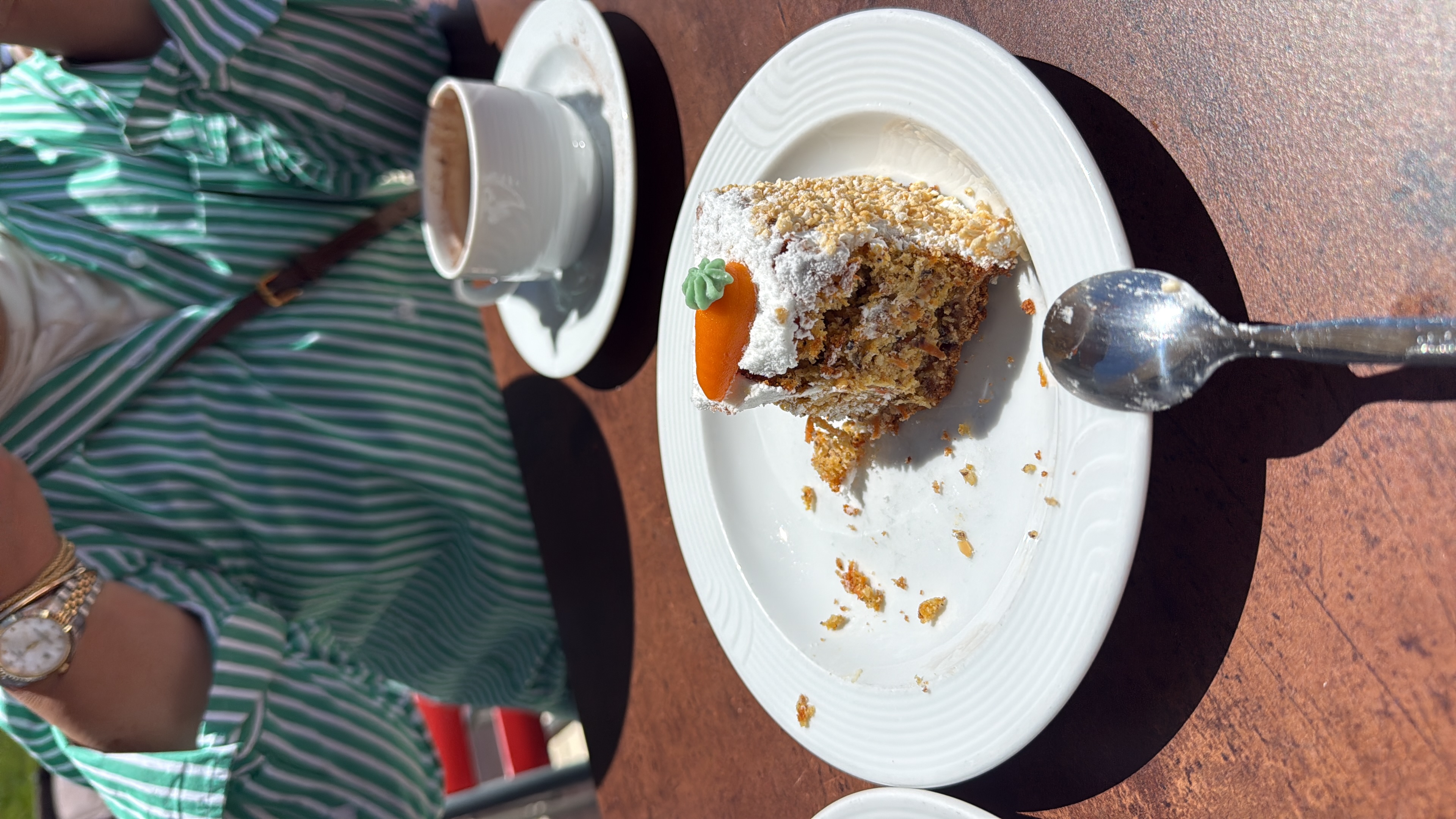 A slice of carrot cake with its marzipan carrot, and a warm coffee.