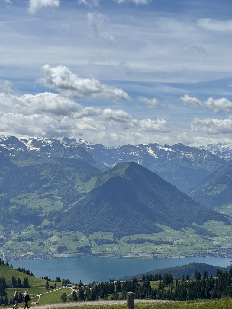Snow-capped Alps and a green peak above the blue lake.